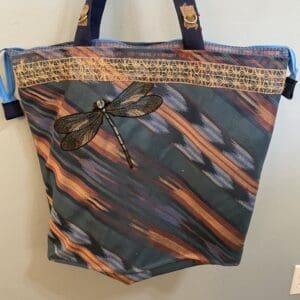 Striped tote bag with dragonfly applique.