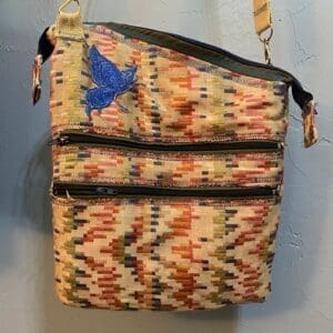 A bag hanging on the wall with two zippers.