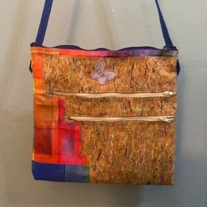 A bag made of cork with blue handles and a butterfly on the front.