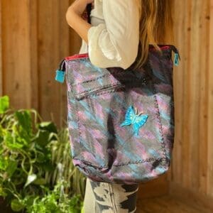 A girl is holding onto her purse and looking at the camera.