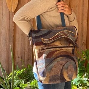 A person holding onto a bag with a brown and blue pattern