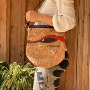 A woman holding onto a cork purse with red handle