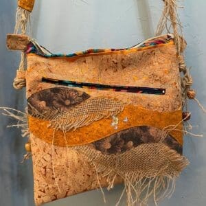 A bag made of cork and fabric with a strap.