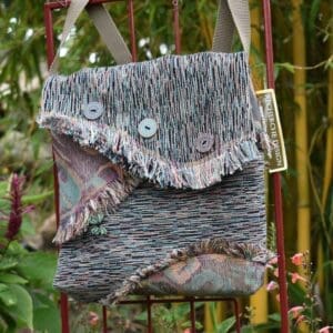 A bag hanging on the side of a metal fence.