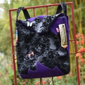 A purple bag with black lace and butterfly design.